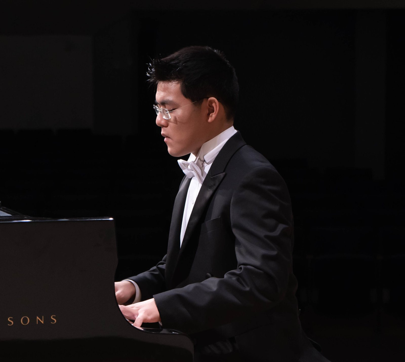 Bowen Duan standing next to a Steinway & Sons Grand Piano